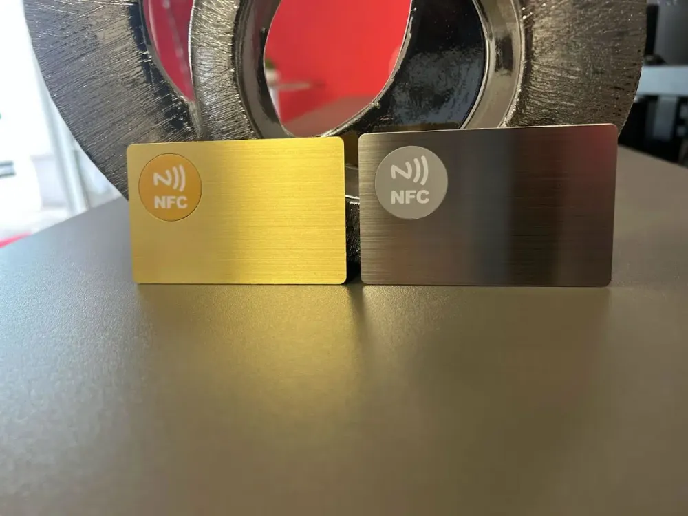 Goldene und schwarze NFC-Metallkarten vor einer Lasergravurmaschine